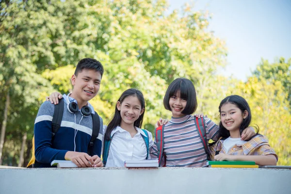 Cuatro estudiantes adolescentes de pie en la escuela y sonriendo —  Fotos de Stock