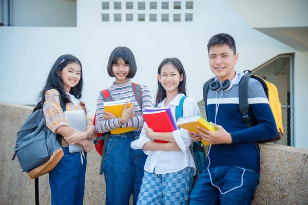 Dört genç öğrenci okulda durup gülümsüyor. — Stok fotoğraf