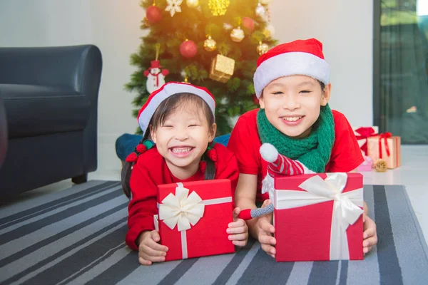 Klein aziatisch meisje en haar broer liggen op de vloer met geschenkdoos — Stockfoto