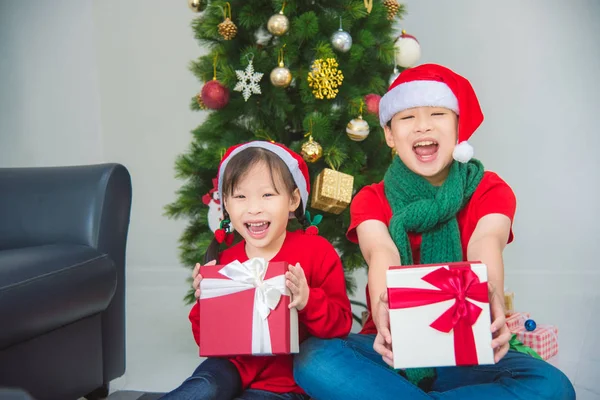 Klein aziatisch meisje en haar broer zitten op de vloer met geschenkdoos — Stockfoto