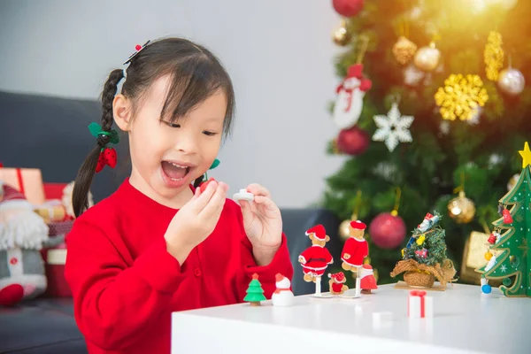 Klein meisje spelen puzzel in de voorkant van kerstboom. — Stockfoto