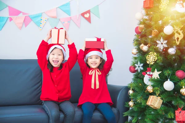 Two little asian girls wearing santa claus hat and holding gift box — Stock Photo, Image