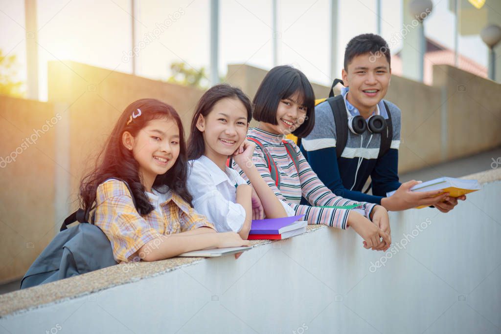 Four asian teenager students standing in school and smiling