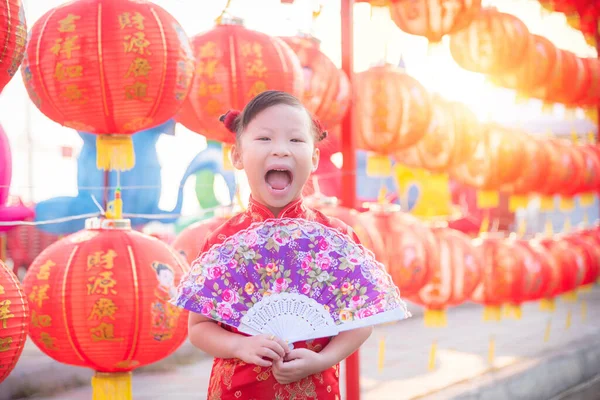 Little azjatyckie dziewczyna sobie chiński tradycyjny kostium stojący z czerwoną latarnią i uśmiechnięty — Zdjęcie stockowe