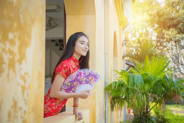 Hermosa chica asiática en traje tradicional chino sosteniendo ventilador y sonriendo . — Foto de Stock