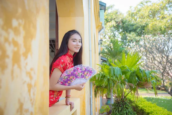 Schöne asiatische Mädchen in chinesischer Tracht mit Fächer und Lächeln. — Stockfoto