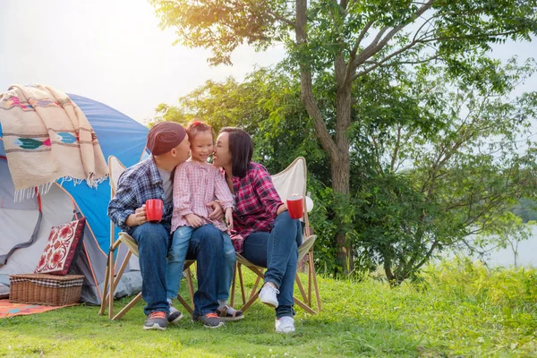 Pareja feliz sentada en el camping y besando a su hija . — Foto de Stock
