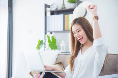 Kanepede oturan ve bilgisayar kullanan güzel bir kız..