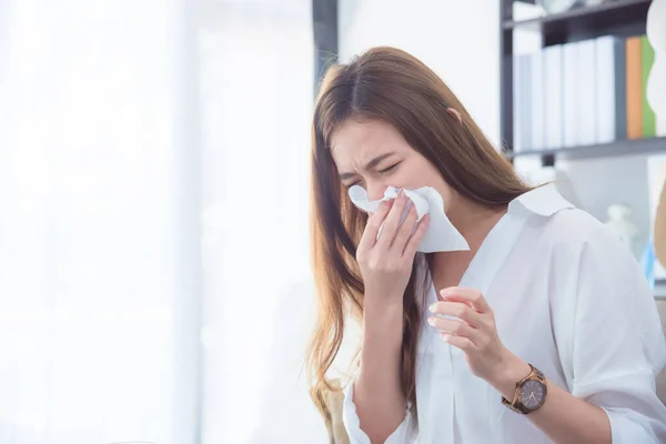 Mujer joven que tiene la nariz corriendo, se limpia la nariz con papel tisú . — Foto de Stock