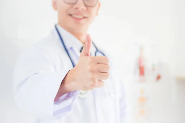 Asian male doctor smiling with giving thumb up with copy space. Focus at doctor hand.