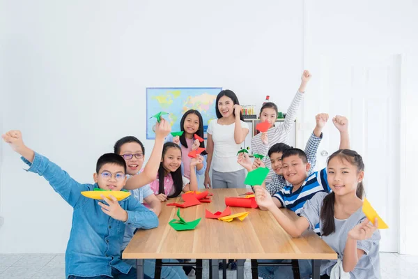 Bir Grup Asyalı Öğrenci Bir Öğretmen Sınıfta Kağıt Uçağını Gösteriyor — Stok fotoğraf