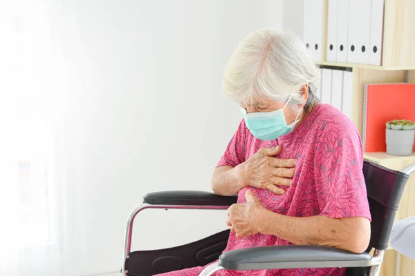 亚洲老年妇女戴着口罩坐在轮椅上 胸痛咳嗽 — 图库照片