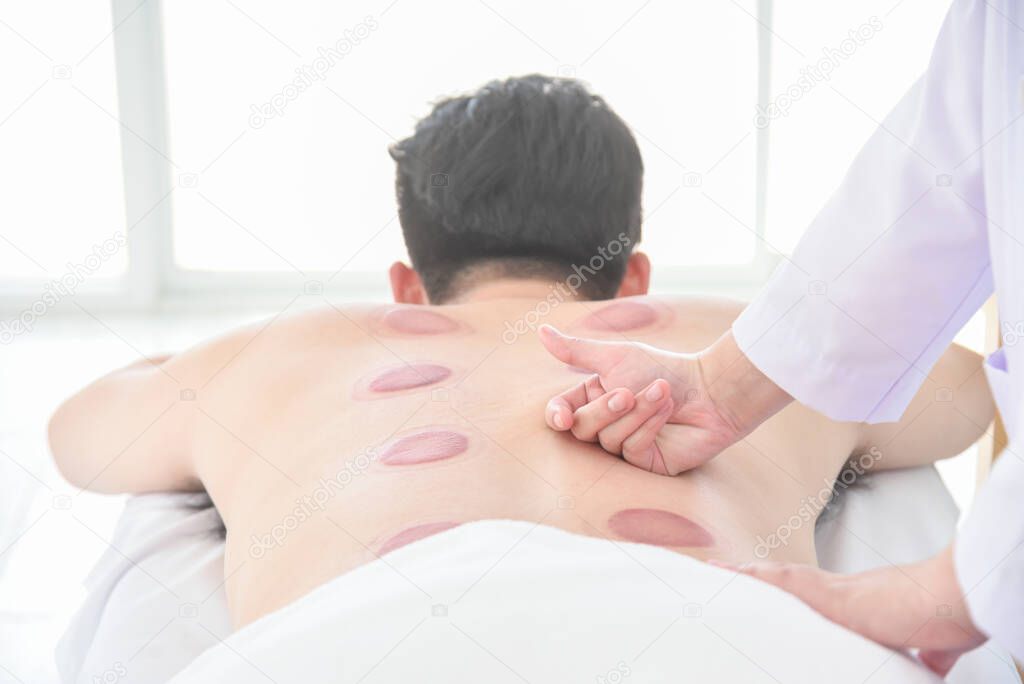 Therapist doing Tui na massage for her patient after cupping therapy finished ,Chinese alternative medicine.