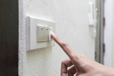 kadın bir evde ışık anahtarı devre dışı bırakarak