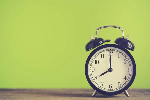 Reloj despertador retro en mesa de madera con fondo verde, vintage — Foto de Stock