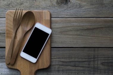 cep telefonu ile çatal ve kaşık ahşap tabakta servis kavramı bir