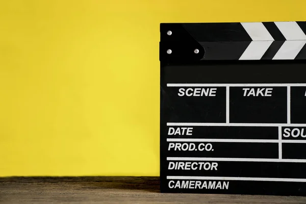 Κλακέτα ταινία σε ξύλινο τραπέζι με κίτρινο φόντο? ταινία, cinem — Φωτογραφία Αρχείου