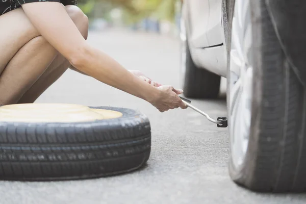 Mujer cambiando de rueda en una carretera — Foto de Stock