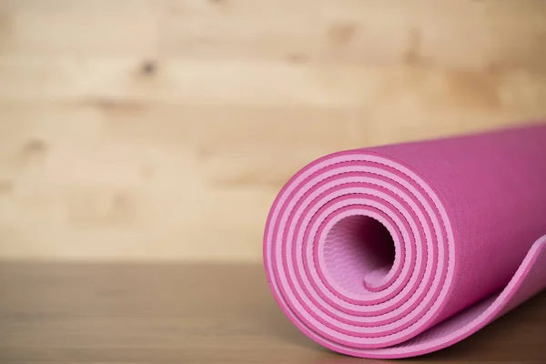 Primer plano de estera de yoga rosa sobre la mesa, deporte y cóncavo saludable — Foto de Stock