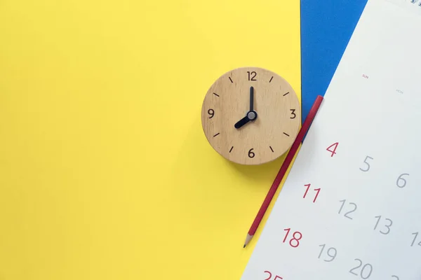 Close up de calendário, relógio e lápis no amarelo e azul ta — Fotografia de Stock