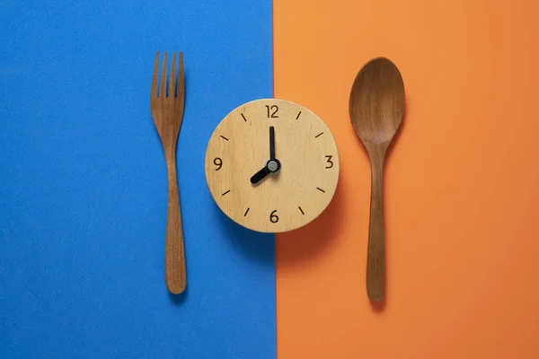 Jídlo hodiny lžička a vidlička, Zdravé jídlo koncept na modré a oran — Stock fotografie