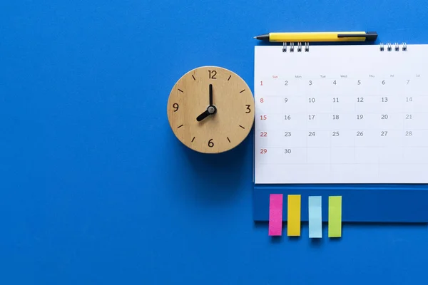 Close up of calendar and alarm clock on the blue table backgroun — Stock Photo, Image