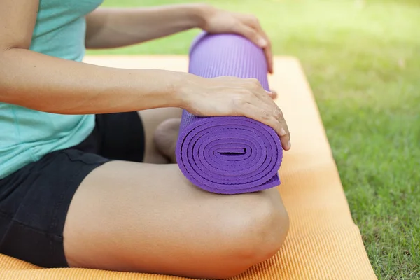 Mujer joven sosteniendo una esterilla de yoga en clase de ejercicio para un deporte y — Foto de Stock