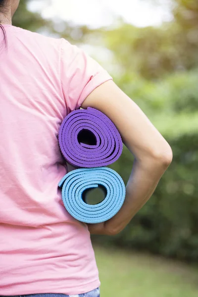 Молодая женщина держит циновку йоги в классе упражнений для спорта и — стоковое фото