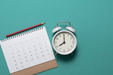 yeşil masa üzerinde takvim ve çalar saat yakın, plannin