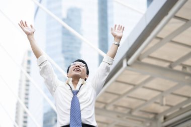 Asyalı işadamı ellerini hareket ettirerek, başarılı olarak ve anlık iş konseptini neşelendirerek memnuniyetini ya da mutluluğunu gösteriyor.