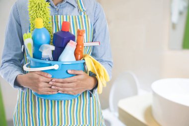 Elinde temizlik malzemesi olan bir kadın banyodaki ya da tuvaletteki evi temizlemeye hazır.