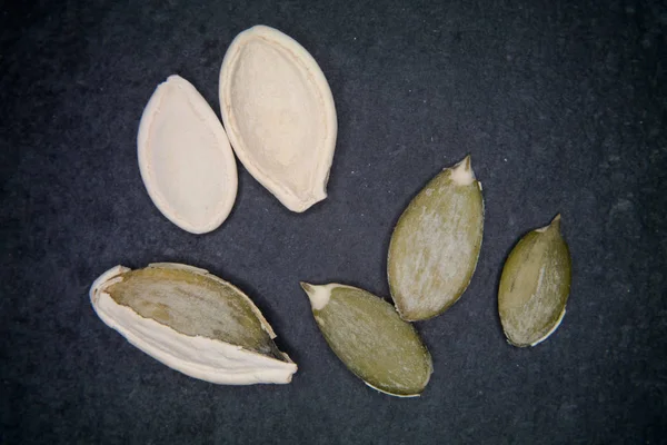 Graines de citrouille entières et pelées sur ardoise — Photo