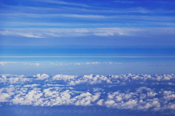 Nubes esponjosas y cielo azul vistos desde el asiento de la ventana de un aeropl — Foto de Stock