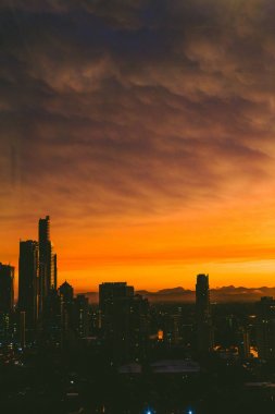 kıyı şeridi ve Surfe binaların üzerinde dramatik turuncu günbatımı