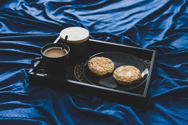 breakfast tray in bed with peanut butter crumpets and coffee mug
