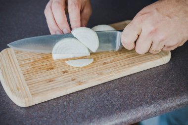 Şef tahtanın üzerinde soğan doğruyor.