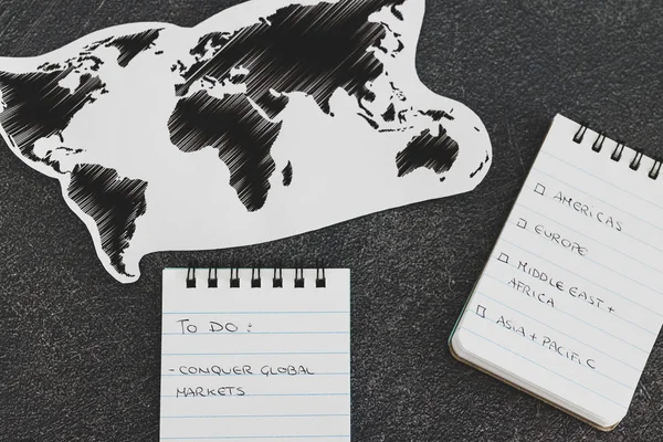 Conquering global markets, world map and text on to do list on b — Stock Photo, Image
