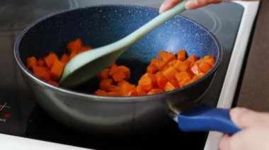 butternut squash cubes getting sauteed and stirred in a pan on stovetop, meal-prepping healthy food concept
