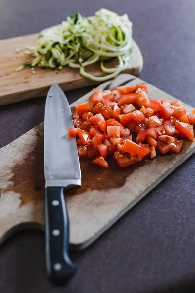 Tomates cortados en cubitos con cuchillo en tabla de cortar —  Fotos de Stock