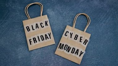 marketing promotional offers and sales conceptual still-life, hand placing payment card next to Cyber Monday and Black Friday shopping bags