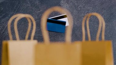 marketing promotions and customer purchasing habits conceptual still-life, payment cards in the distance framed by shopping bags in the foreground and camera panning vertically