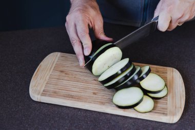 Patlıcan dilimleri kesen bir adam.