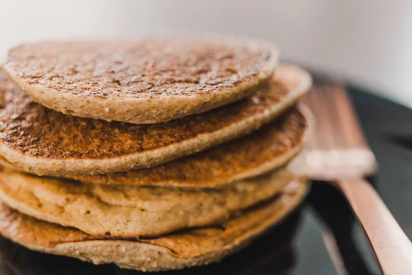 Close-up of vegan banana pancakes stack on black plate with copp — Stock Photo, Image
