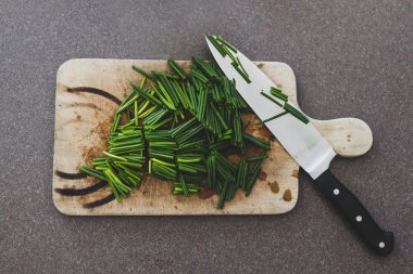 freshly cut chive on chopping board with knife next to it