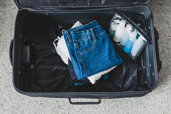 Packing light for a holiday concept, luggage with pile of clothe — 스톡 사진