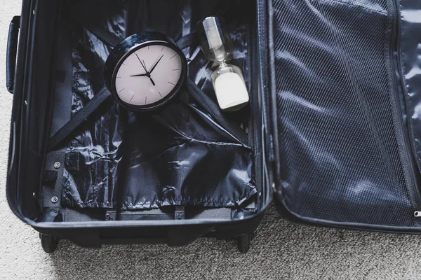 Час подорожі або затримки під час поїздки, порожня валіза з годинником — стокове фото