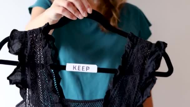 Woman Holding Clothes Hangers Black White Tops Text Labels Sort — 비디오