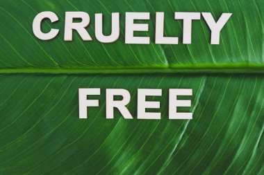 Acımasızlık. Tropikal muzun tepesinde ahşap harflerle yazılmış ücretsiz metin. 