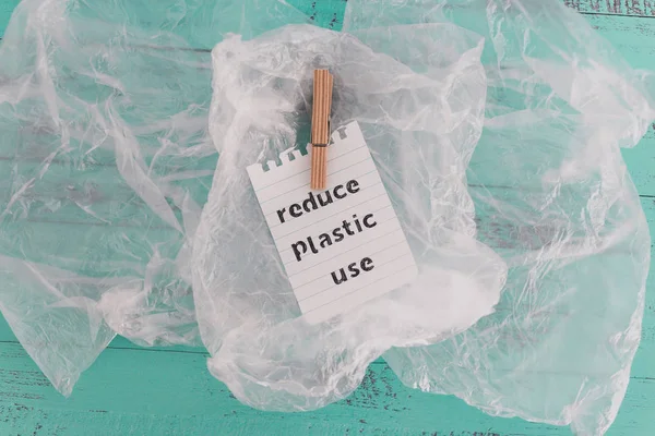 Reduce plastic use message with wooden peg on top of plastic bag — Stock Photo, Image