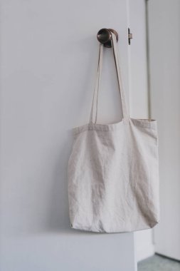 Alışveriş ve günlük hayat kavramsal natürmort bez çanta, gardırop kapısının önünde el ele tutuşan minimalist görünümlü.